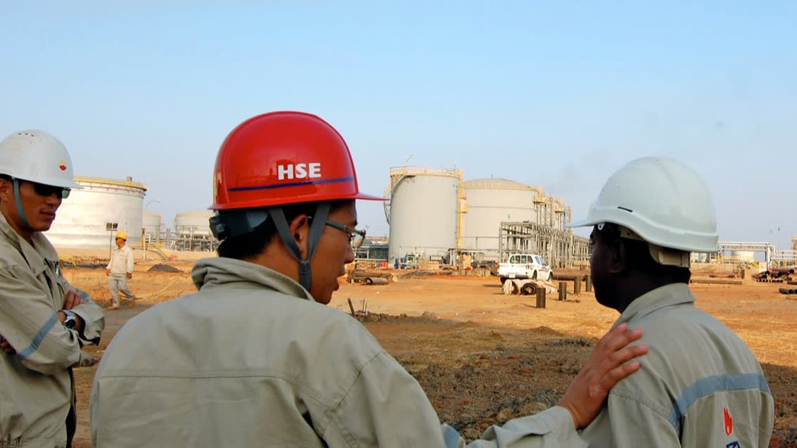 A Chinese worker talks to his colleague at an oil production facility in Sudan in December 2010: China's foray into Africa coincided with the peak of the commodity supercycle.