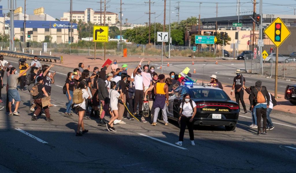 Demonstrators swarm a California Highway Patrol cruiser on the Hollywood Freeway in Los Angeles on Wednesday