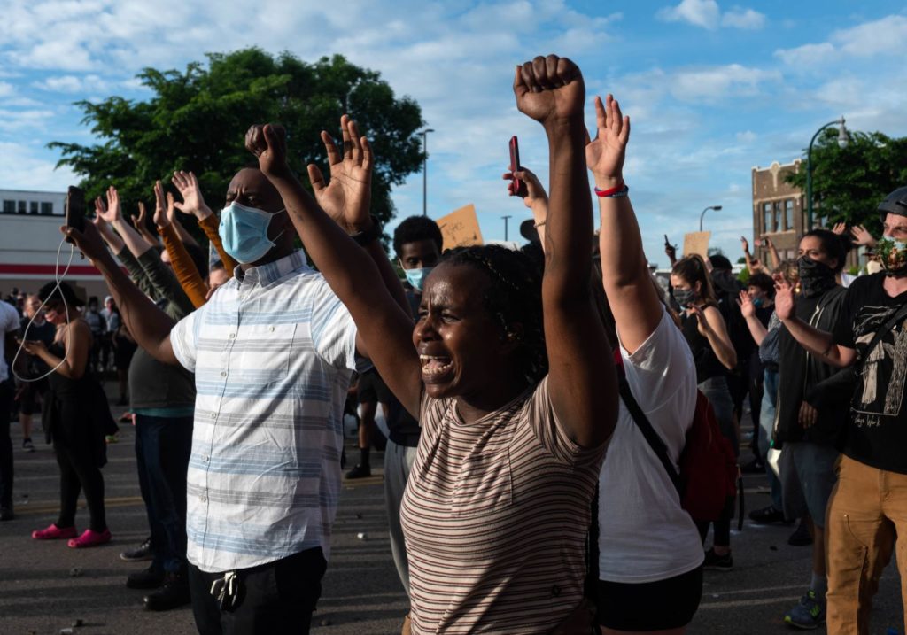 Demonstrators in Minneapolis raise their hands as they standoff with police